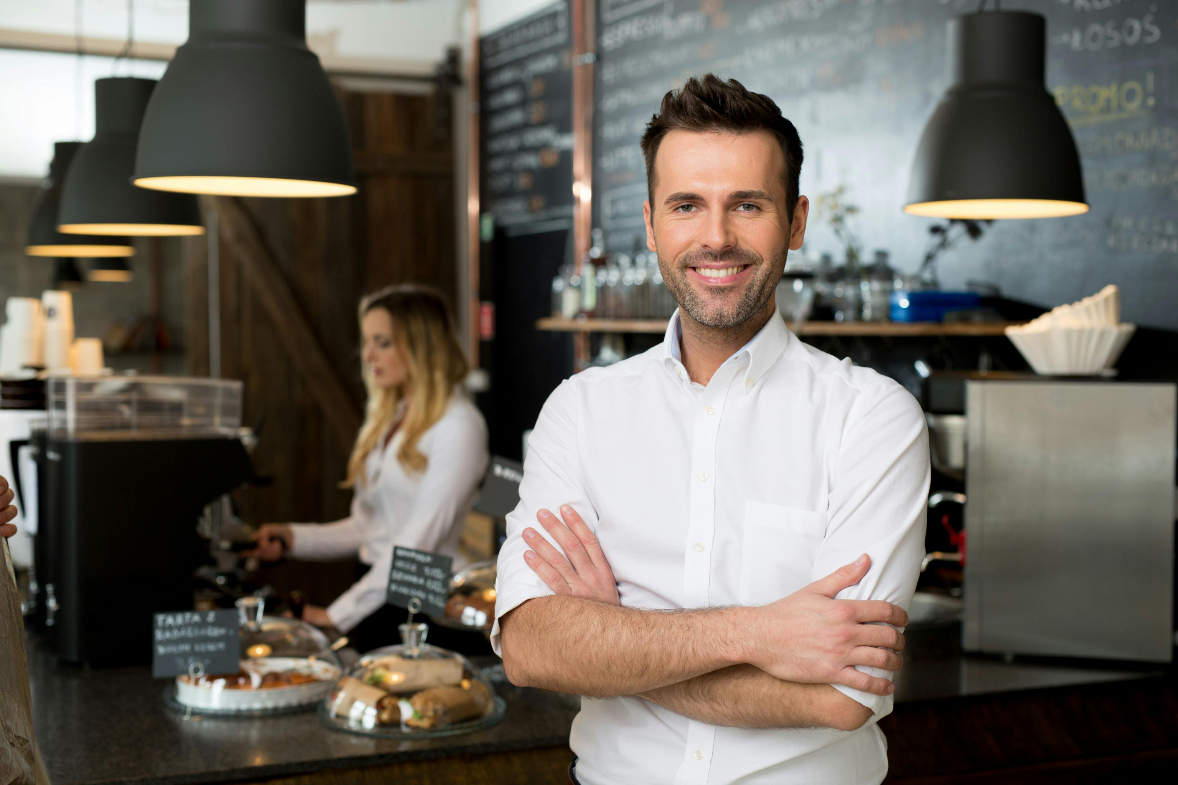 Restaurant manager standing with arms crossed in front of coffee shop.
