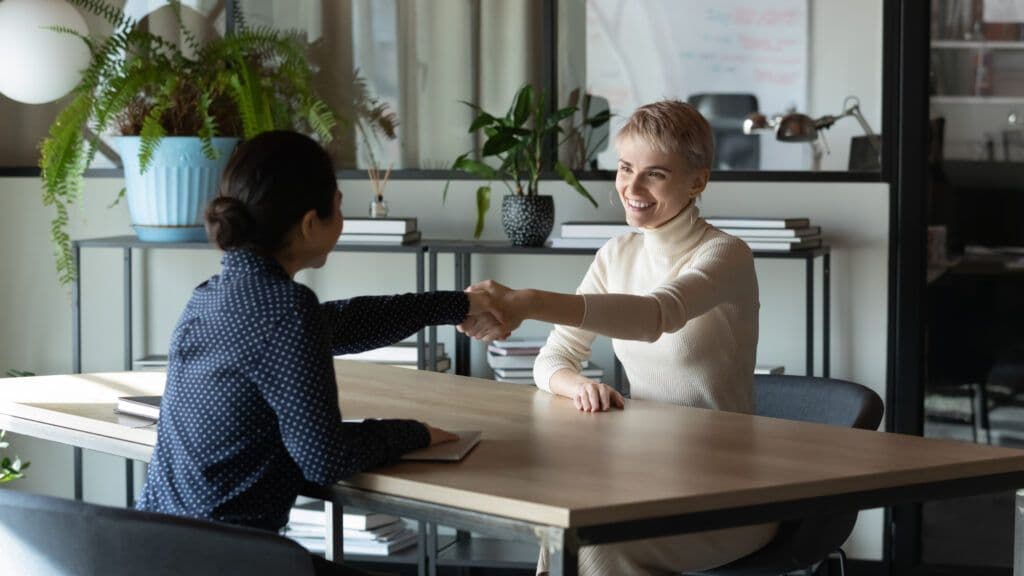 Businesswomen shaking hands, discussing restaurant service standards.