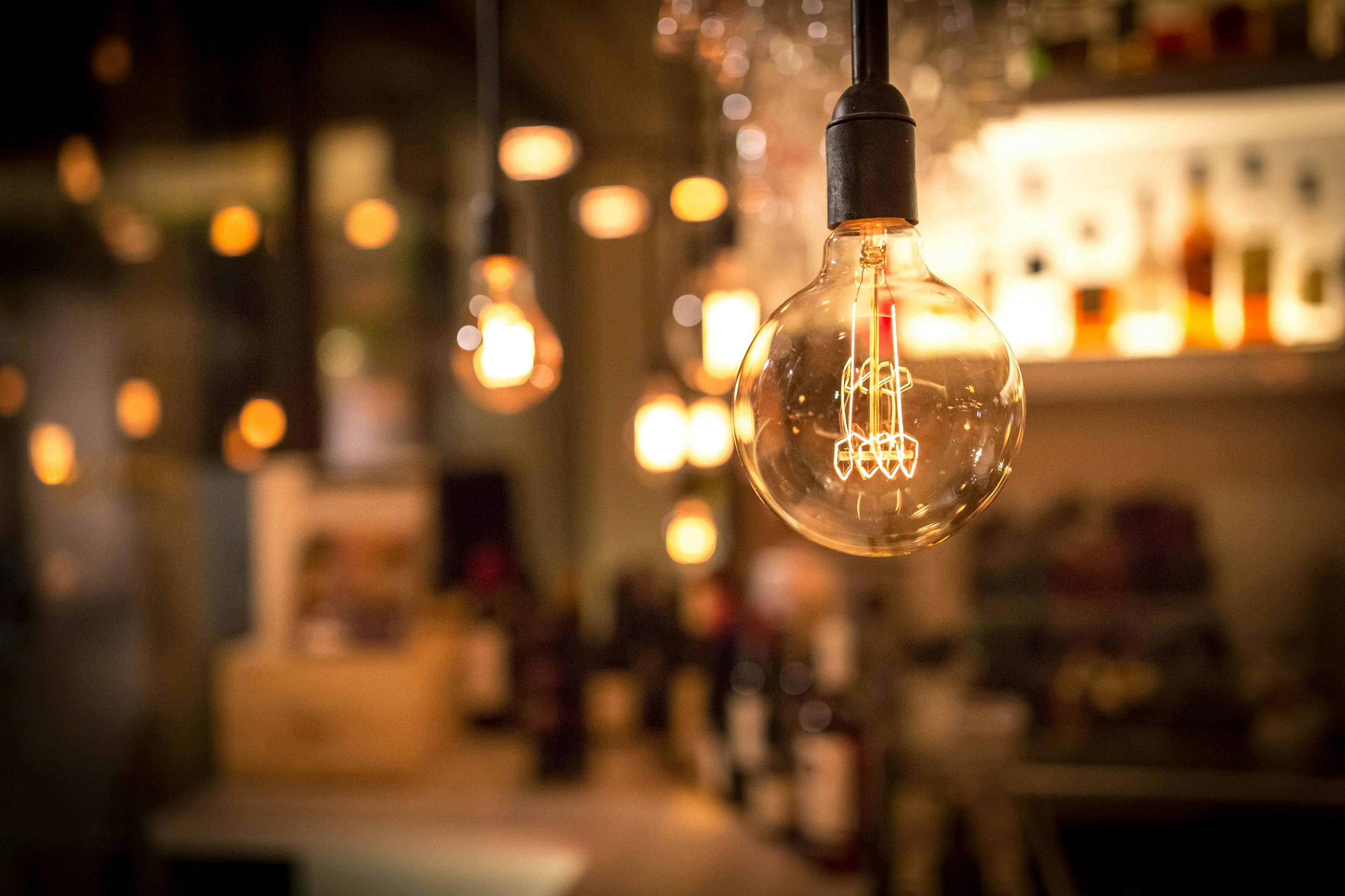 A bar scene captured up close, featuring multiple light bulbs emitting energy-efficient illumination, promoting energy-saving tips for restaurants.