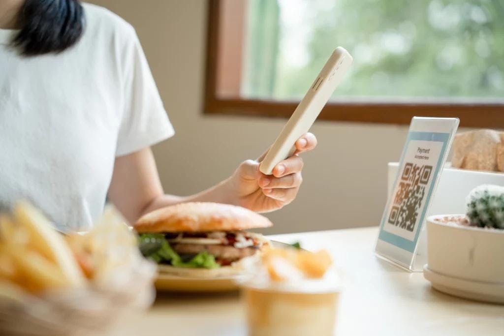 A woman using a smartphone to order food from a free QR menu.
