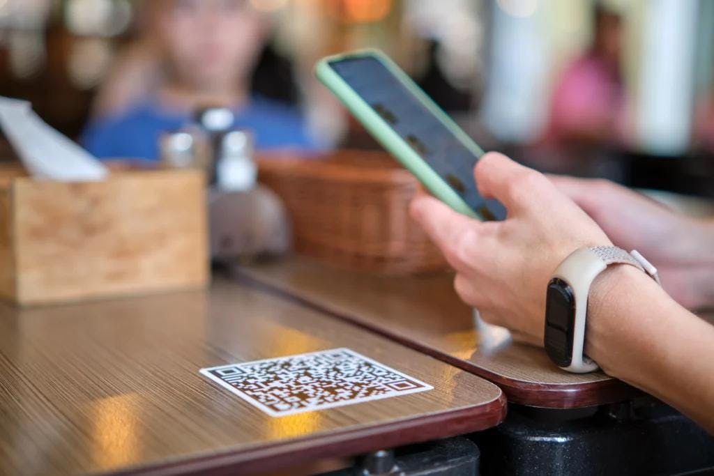 A person using a smartphone at a table, engaged in the 'Order & Pay' process.