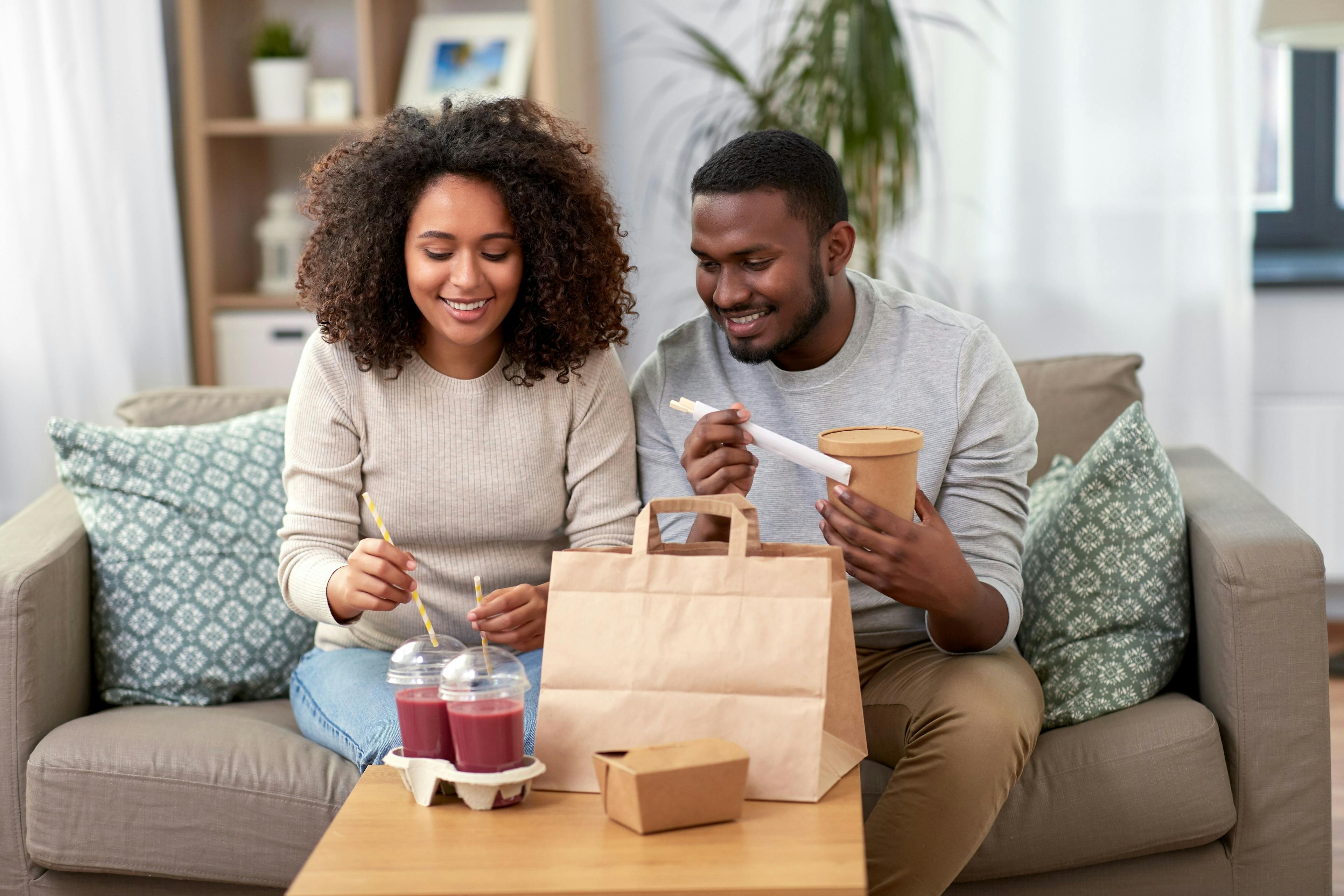 A young couple enjoying takeout lunch on the couch.
