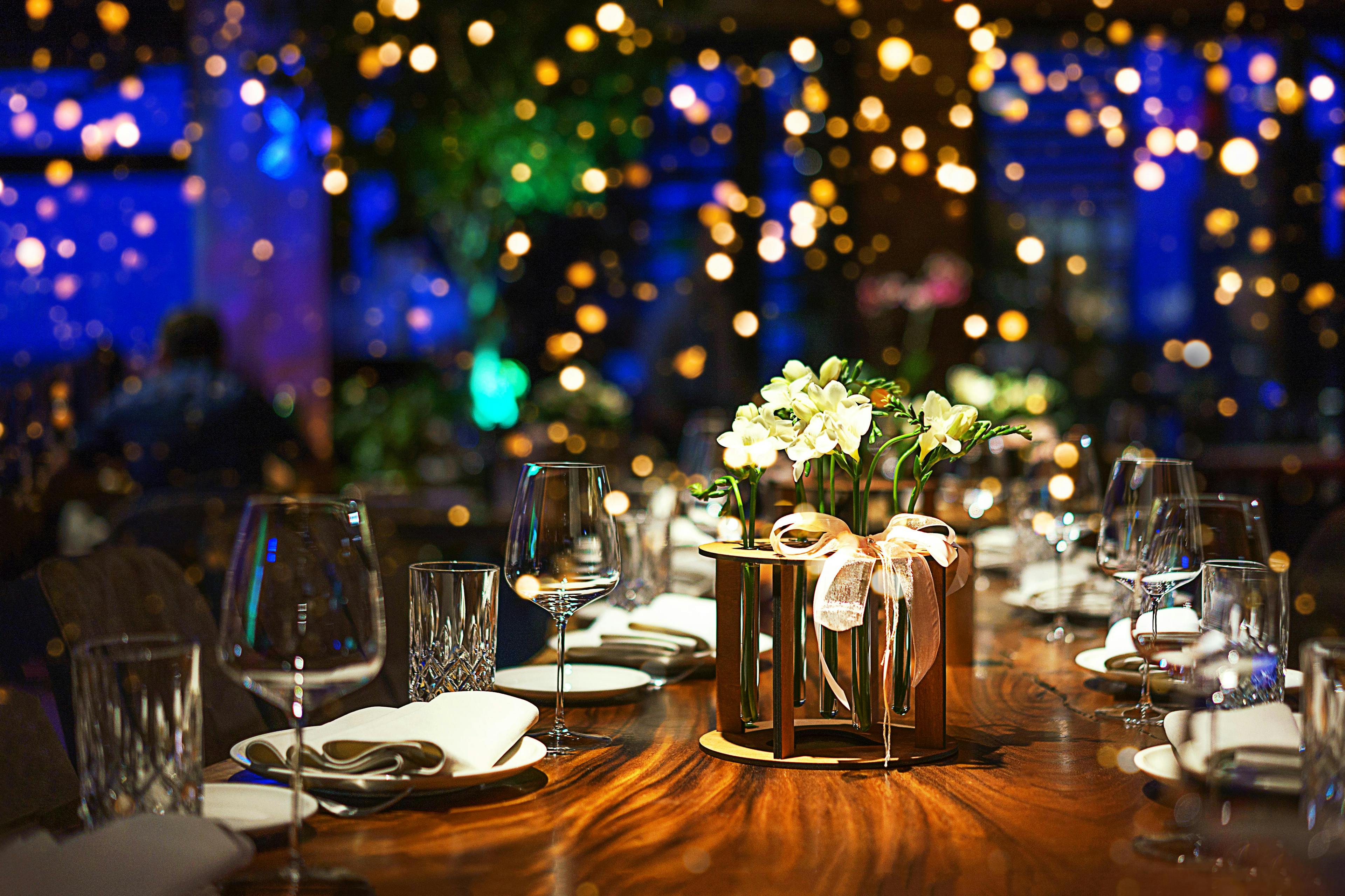 Festive dinner table with lights in background for New Year's Eve celebration.