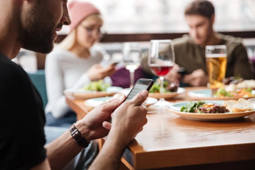 Customer on phone at table with food and searching Fast checkout option.