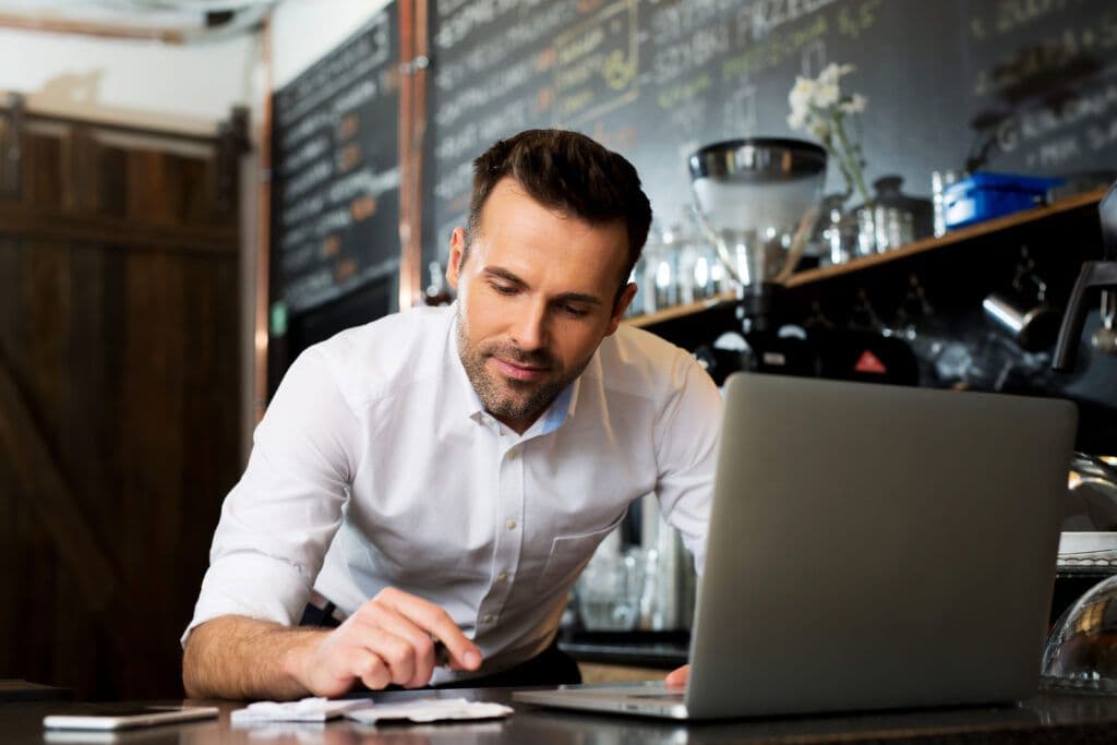 A man intently working on his laptop, handling restaurant revenue management.