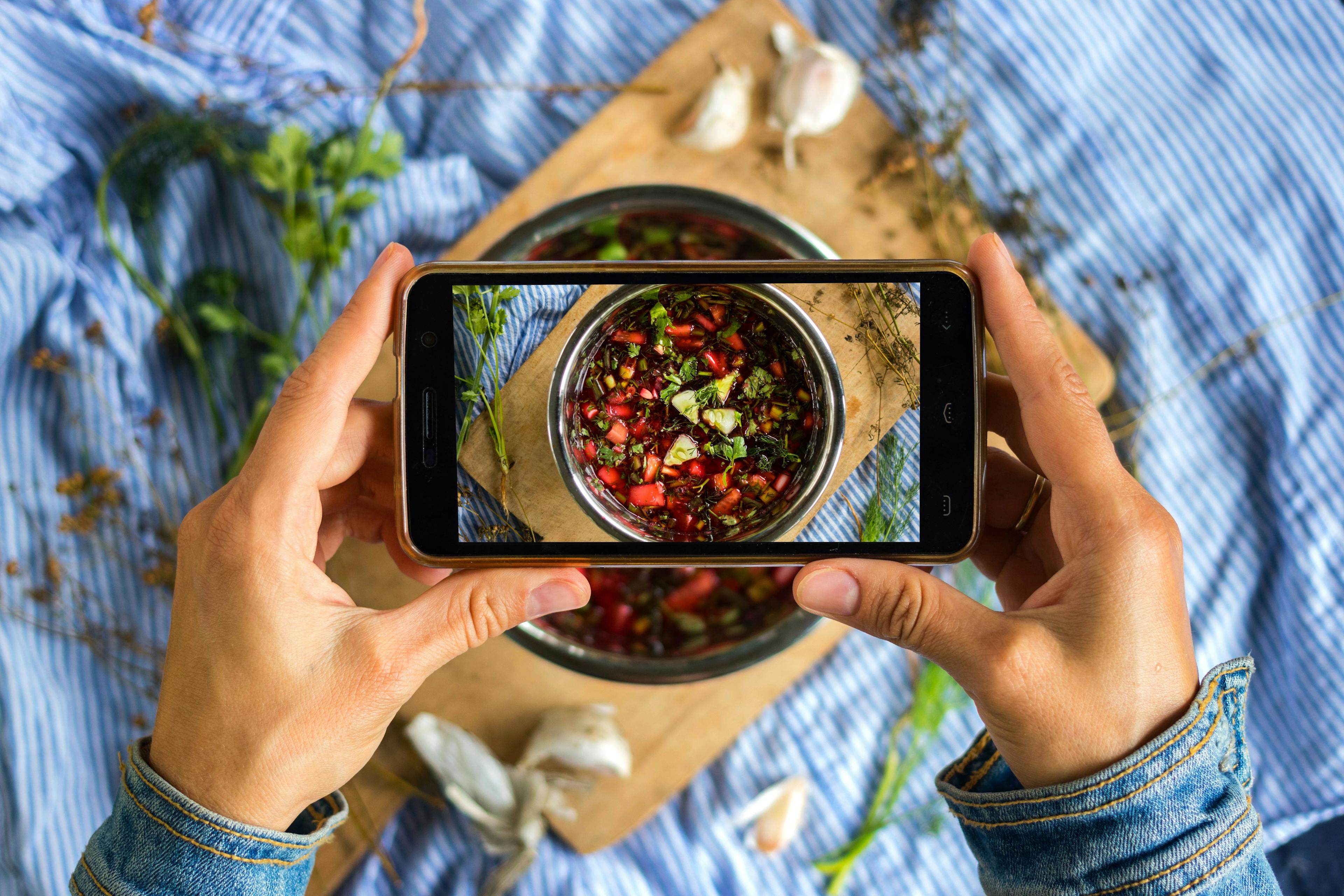 A person using their phone to snap a picture of a delicious bowl of food, with the intention of posting it on Instagram.