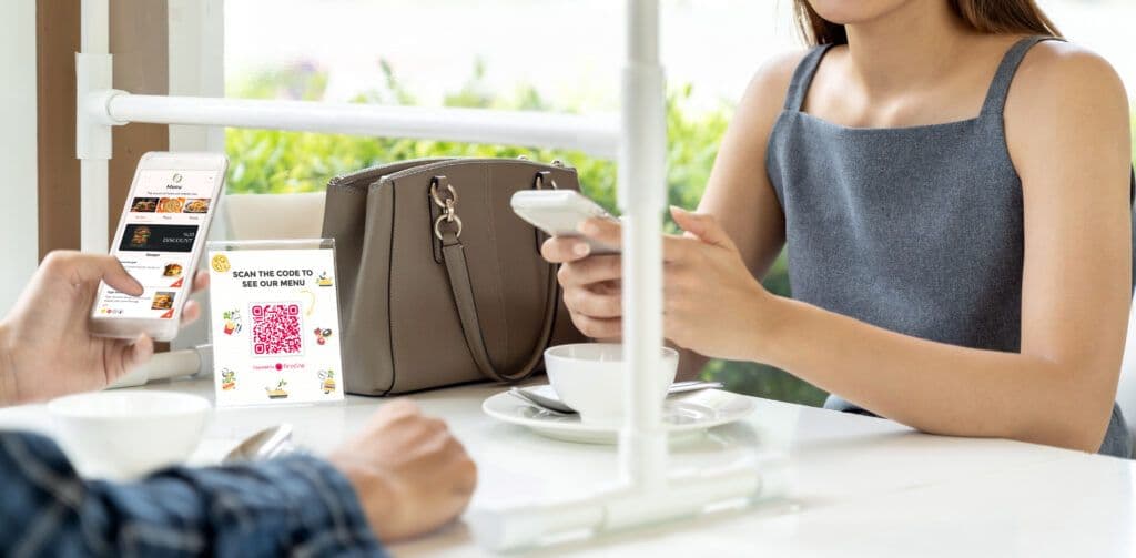 A man and woman seated at a table and using a QR menu.